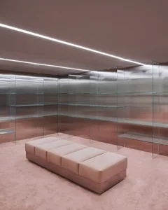 A minimalist retail store with glass shelves and polished concrete flooring.