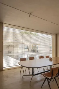 Modern dining room with a wooden table and chairs, featuring a minimalist design with transparent blinds.