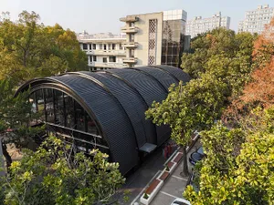 A modern library with a metal-roofed exterior surrounded by greenery.