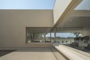 Minimalist modern pavilion with glass walls and concrete flooring.