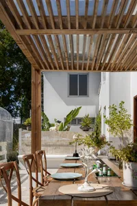 A minimalist outdoor dining space featuring wooden tables, glass decor, and concrete elements.
