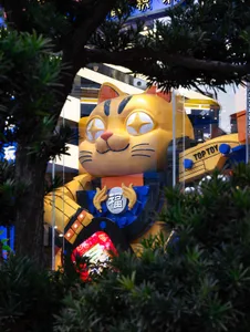 A large, colorful toy cat display in a retail storefront window.