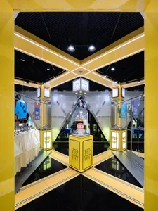 A retail store with metallic yellow lighting, black floor, and a prominent toy figure on a yellow pedestal.