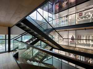 Modern industrial trim store with black metal staircase and glass railing, featuring a variety of products displayed on pegbo