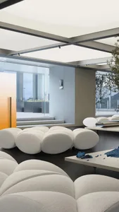 Modern minimalist living room with white textured upholstery, glass elements, and metal accents.