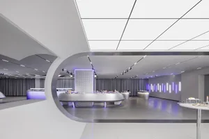The interior of a minimalist retail space featuring white metallic surfaces and reflective finishes.