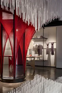 A modern clothing store with metal and fabric architectural elements and a retail display of clothing and accessories.