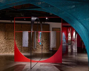 Modern fashion retail space featuring red canvas walls and metal structures.