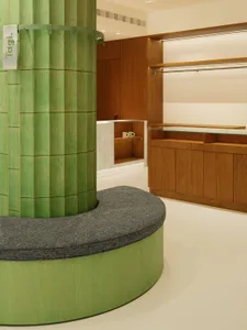 A modern office space featuring green wood columns and white tiled flooring.