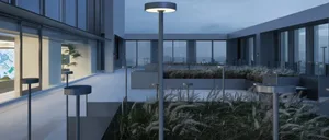 Modern outdoor space featuring concrete, glass, and plants.