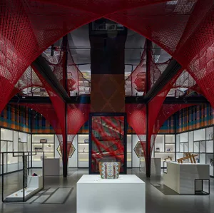 Modern retail space with red netting installation, glass showcases, and glass walls