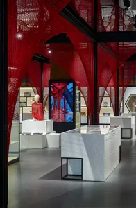 Modern retail store with red netting, white display cases, and glass walls.