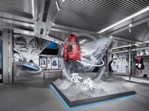 Fashion retail display featuring a red jacket mounted on a white mountain, surrounded by rock formations and a blue backgroun