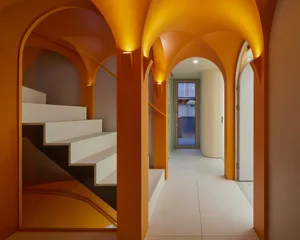 Modern interior design featuring a concrete staircase and corridor with arched ceilings and warm lighting.