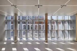 Modern interior space featuring glass walls, steel columns, and archways.