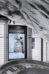 Modern retail storefront with duotone color scheme featuring a mannequin displaying a winter jacket with a fur-lined hood.