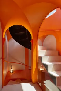 A vibrant orange interior with concrete stairs and arched doorways.