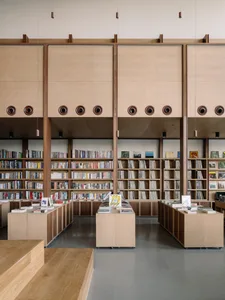 An organized bookstore featuring tall wooden shelves filled with books, with modern design elements.