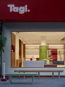 Modern storefront with green ceramic columns and wooden furniture.