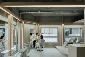 A modern salon featuring minimalist design with concrete walls and white furniture.