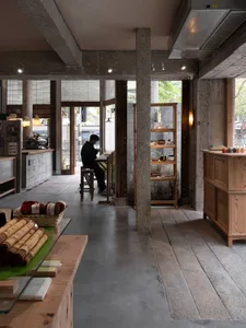 Interior of a coffee shop featuring concrete and wooden materials.