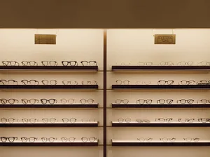 Various pairs of eyeglasses displayed on shelves in a retail store.