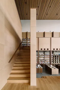 A modern industrial-style library with dual-level wooden shelves and a wooden staircase.