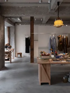 An industrial retail space featuring a wooden display table with various products and clothing items.