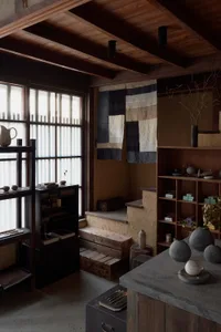 A minimalist residential kitchen featuring wooden elements, stone surfaces, and fabric accents.
