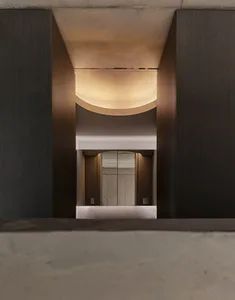A modern entrance hall with a concrete ceiling and floor, featuring illuminated architectural details.