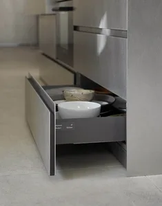 A modern kitchen with metallic cabinets and an open drawer filled with dishware.