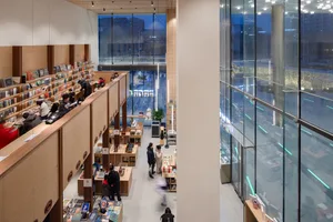 View of a library interior featuring modern design elements such as concrete, glass, and wooden surfaces.