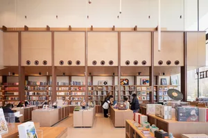 A modern library interior with wooden shelves and glass display cases.