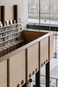A modern library interior with wooden shelves containing various books and magazines.
