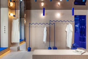 A retail clothing shop with modern design features, including white tiles and blue accents.