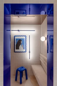A modern, small space with tiled walls, a bench seat, and a unique stool.