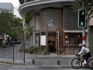 Street view of a wooden and concrete retail shopfront with a green pedestrian signal.