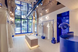 A neatly arranged retail shop displaying white garments on blue accents