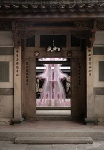 An intricately carved doorway with traditional Chinese symbols, illuminated by modern lighting fixtures.