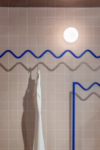 Modern interior design with metal hooks on a tiled wall.