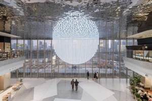 Modern lobby interior featuring metallic ceiling, glass windows, and concrete floor, with a cityscape view outside.