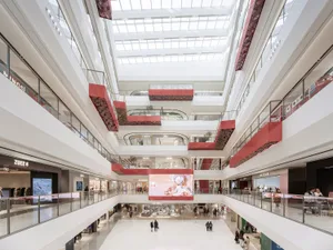 Modern shopping center interior with white marble finishes and red accents.
