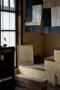 A cozy home interior with textile hangings, wooden steps, and concrete walls.