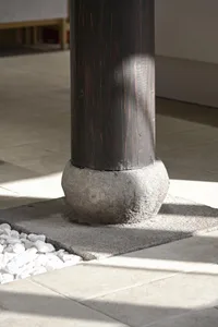 A dark wooden pillar base in a modern interior lobby setting.