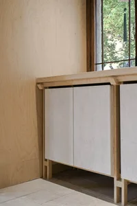 A minimalist cabinet with white doors and wooden flooring.