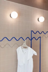 Modern industrial clothing display featuring a minimalist design with a white garment hanging on a metal hanger.