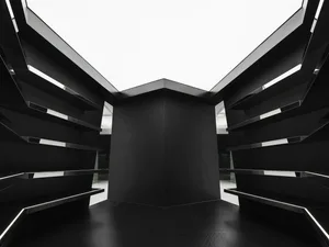 An empty black and white indoor room with geometric shapes and a tall, central structure.