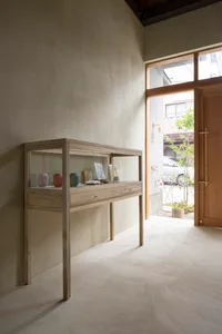 A minimalist retail storefront display case with a modern wood design containing various items.