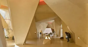 Modern art gallery space with angular architectural features and sandstone concrete walls