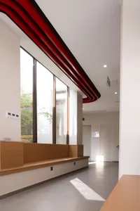A modern interior design featuring a concrete corridor with red beams and large windows.